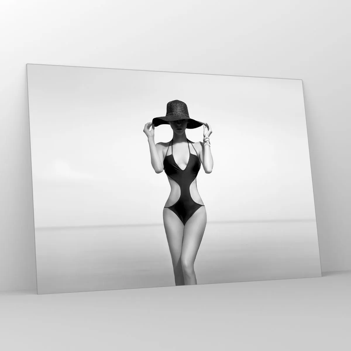 Impression sur verre - Image sur verre - Une femme en maillot de bain noir et chapeau contre la mer - 100x70cm - Mon prénom? Élégance - Décoration murale moderne pour le salon et la chambre ARTTOR