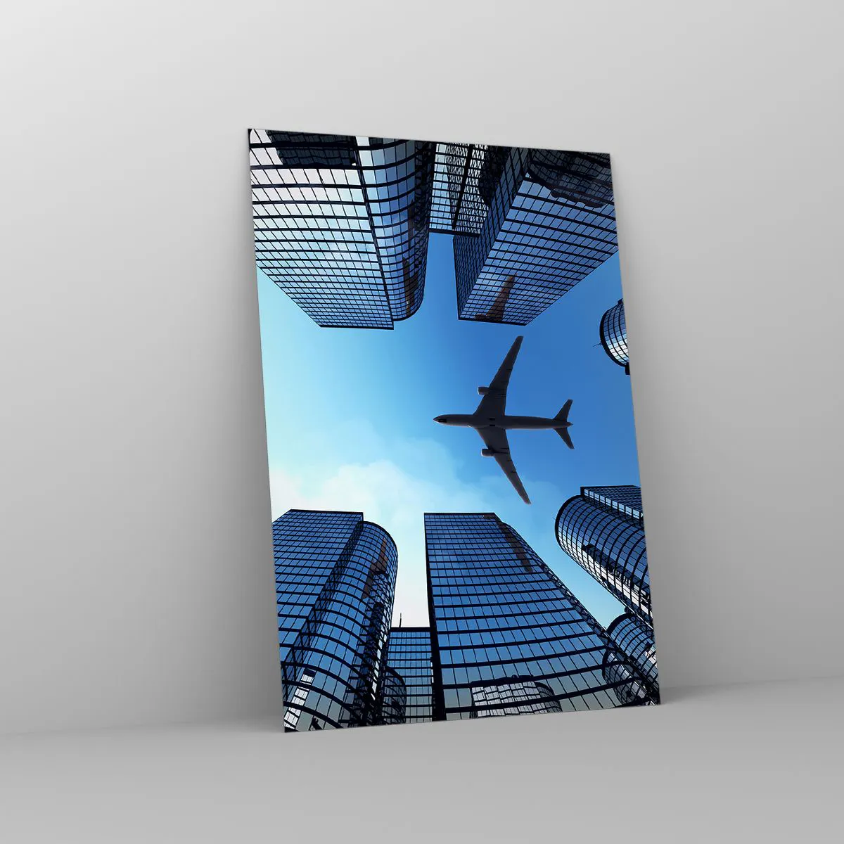 Glasbild - Bild auf glas - Ein Flugzeug fliegt über moderne Wolkenkratzer im Stadtzentrum. - 70x100cm - Der Blick aus der Glasschlucht - Moderne Wanddekoration für Wohnzimmer und Schlafzimmer ARTTOR