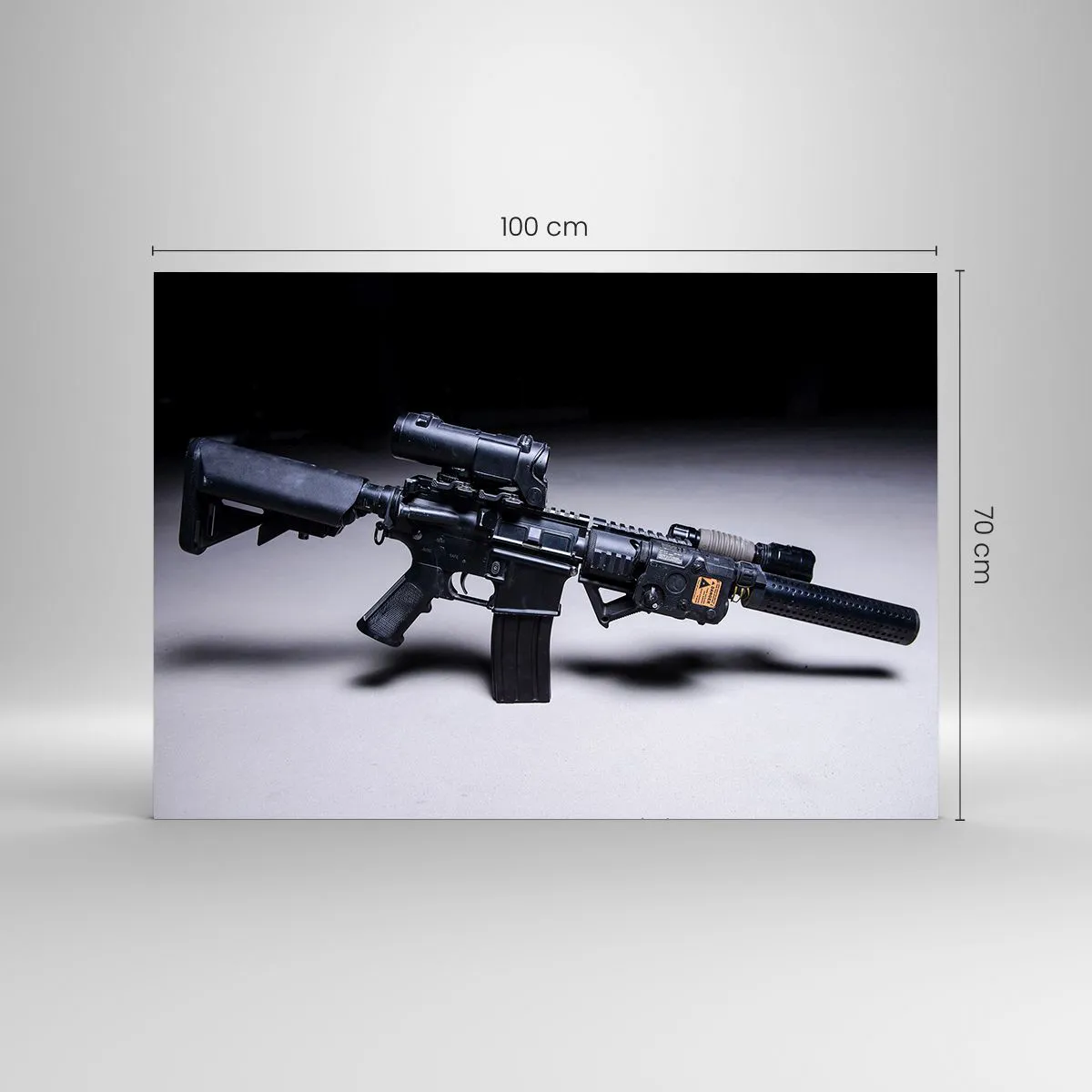 Obraz na szkle - Czarny karabin szturmowy z osprzętem leżący na jasnym tle - 100x70cm - Mroczny rycerz - Nowoczesna dekoracja ścienna do salonu, kuchni i sypialni ARTTOR