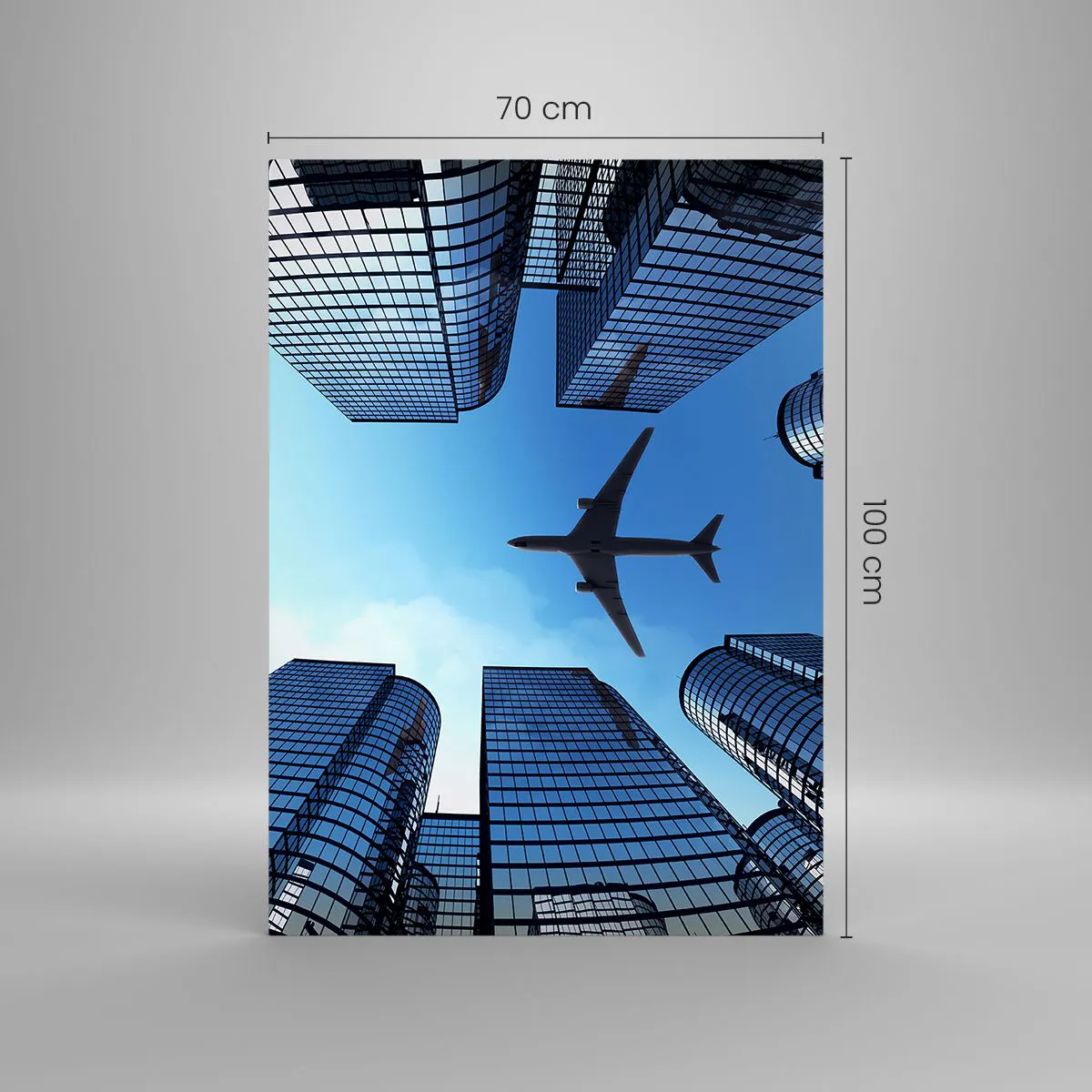 Glasbild - Bild auf glas - Ein Flugzeug fliegt über moderne Wolkenkratzer im Stadtzentrum. - 70x100cm - Der Blick aus der Glasschlucht - Moderne Wanddekoration für Wohnzimmer und Schlafzimmer ARTTOR
