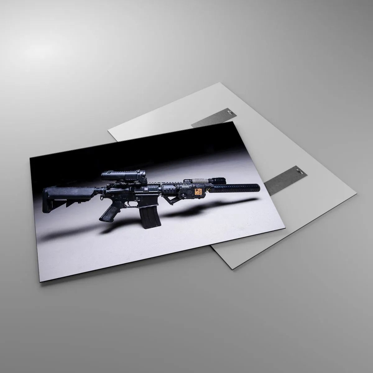 Obraz na szkle - Czarny karabin szturmowy z osprzętem leżący na jasnym tle - 100x70cm - Mroczny rycerz - Nowoczesna dekoracja ścienna do salonu, kuchni i sypialni ARTTOR
