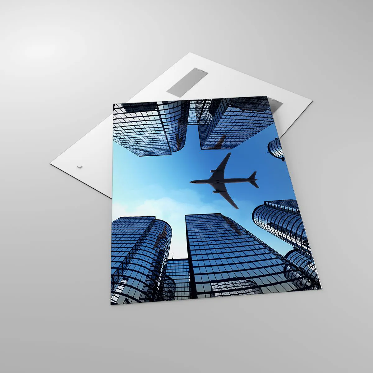 Glasbild - Bild auf glas - Ein Flugzeug fliegt über moderne Wolkenkratzer im Stadtzentrum. - 70x100cm - Der Blick aus der Glasschlucht - Moderne Wanddekoration für Wohnzimmer und Schlafzimmer ARTTOR